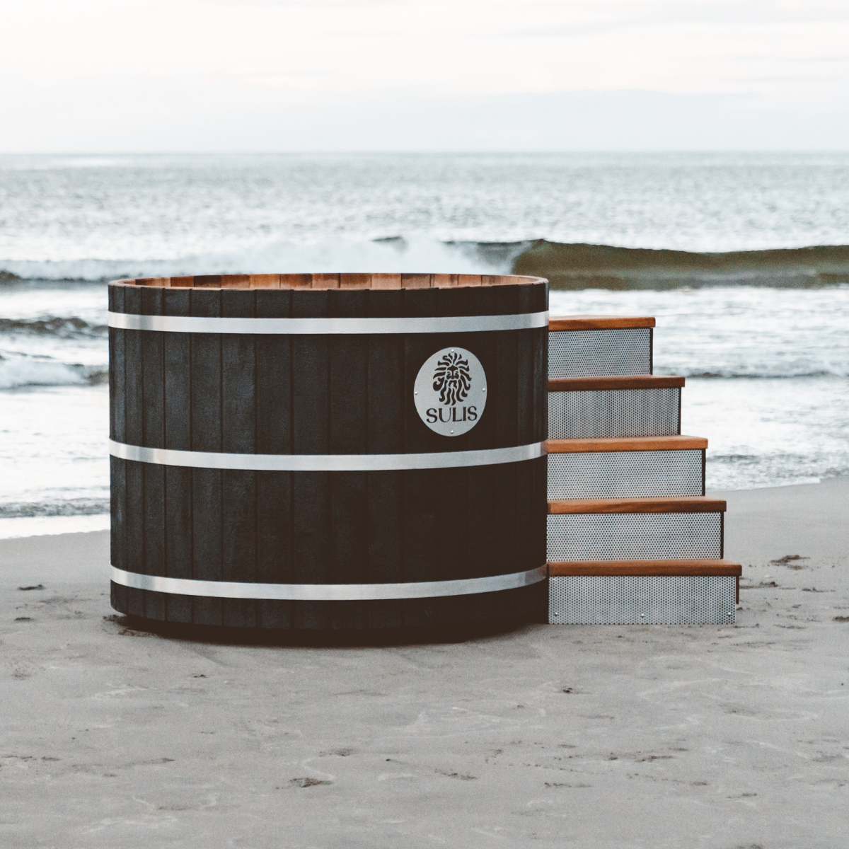 Wooden hot tub with 'Sulis' branding on a beach in black