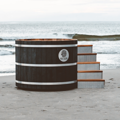 Wooden hot tub with 'Sulis' branding on a beach in black