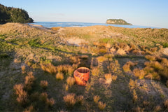 Wooden Hot tub Sulis in a grassy field with ocean and island in the background